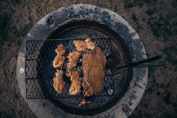 Some meat cooking in the grill on the floor