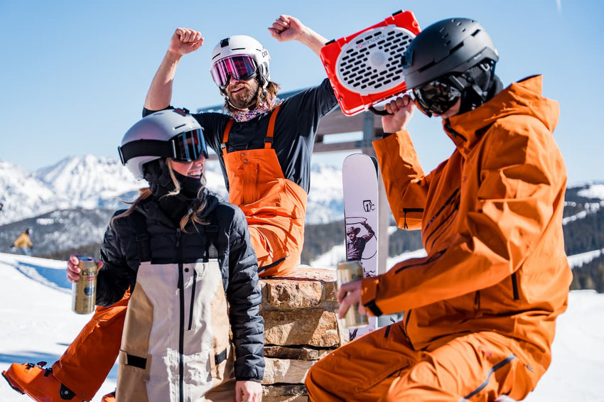 A lifestyle photo of three freeskiers listening music from a  Original Gen 3 Orange speaker