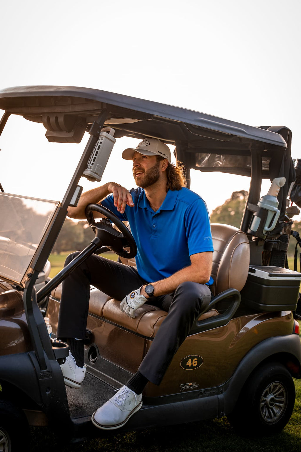 A lifestyle photo from a guy sitted in a golf car with his Ranger speaker in tan attached to the car. #base-color_tan