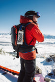 A lifestyle photo of a guy in the snow with Ranger speaker in Ivory attached to his back pack. #base-color_ivory