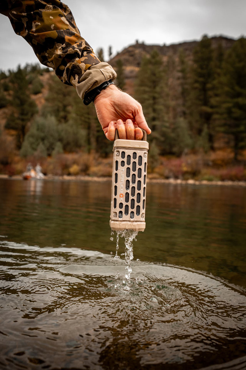A lifestyle photo from a guy removing a Ranger speaker in tan from water. #base-color_tan