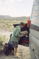 A lifestyle photo of a guy packing wood in a box, listening music from a Ranger orange speaker attached to a car from its magnets #base-color_orange