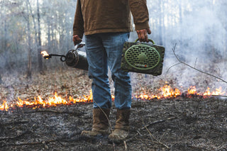 Guy with a gasoline lighter on his right hand is carrying his Mossy Oak Full Foliage speaker in the other hand.