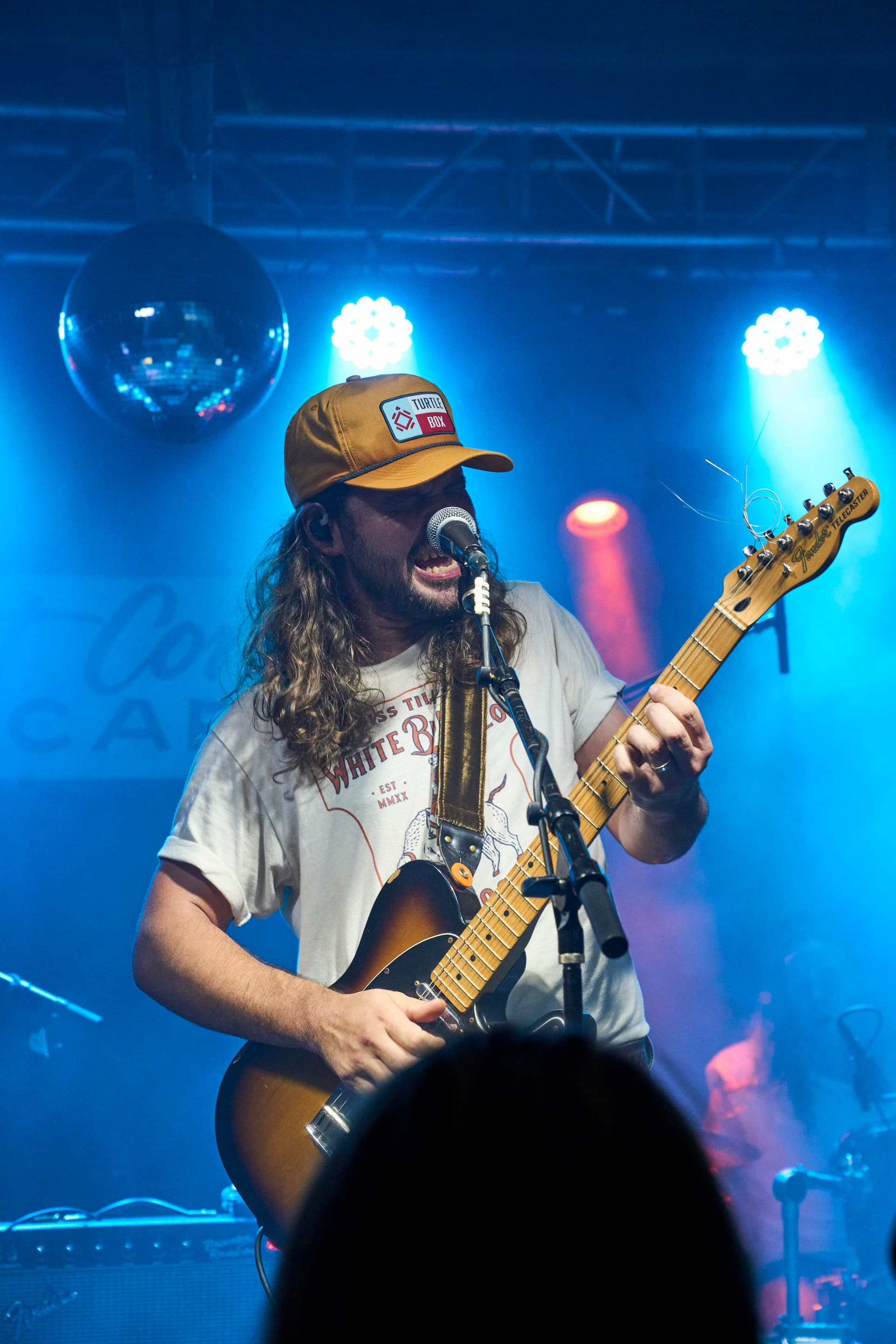 Person playing guitar on stage with microphone and lights