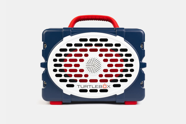 Blue and red portable device with a white grille and 'TurtleBox' branding on a light gray background. no-gallery