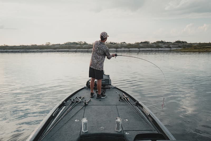 A guy in a boat fishing with two Turtlebox Ranger speakers playing music
