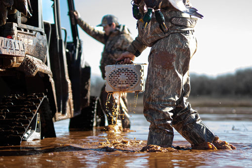 a lifestyle photo showing 2 men in the water, stepping into a vehicle, one of them is holding a white turtlebox dripping water #speaker-color_tan
