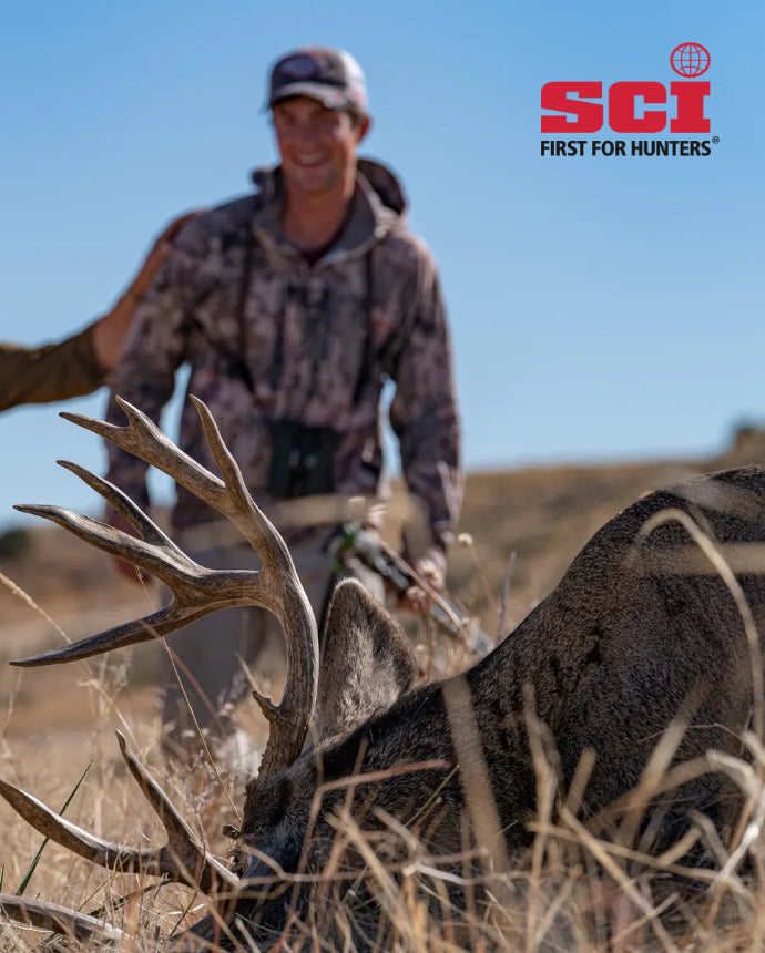 Hunter with a large deer in a field, featuring the SCI logo.