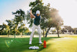 A lifestyle photo from gplfer Scottie Sheffler taking a swing on a golf course with trees in the background #base-color_orange