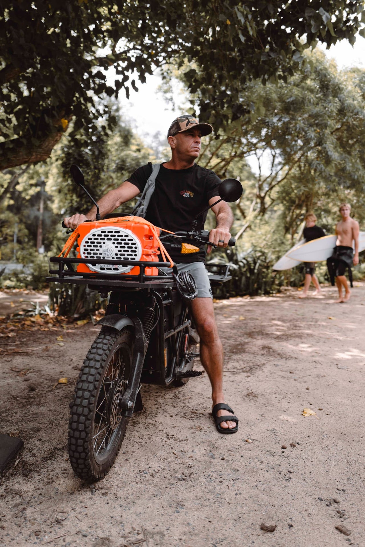 A lifestyle photo from Shane Dorian, our ambassador, driving a motorcycle and carrying a Turtlebox Original speaker in orange color tied up with the straps #speaker-color_orange