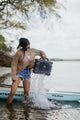 A lifestyle photo from a woman removing a Grande speaker in gray from water. #base-color_gray